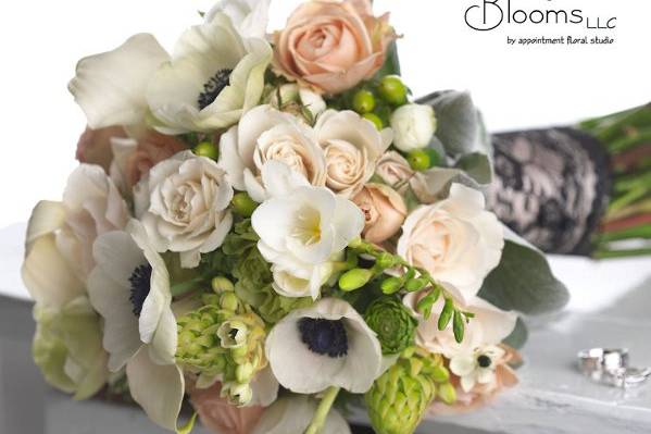 White, blush and green brides bouquet of ranunculus, callas, roses, spray roses, star of bethlehem, hypericum and anemones with a gorgeous black vintage lace stem treatment.