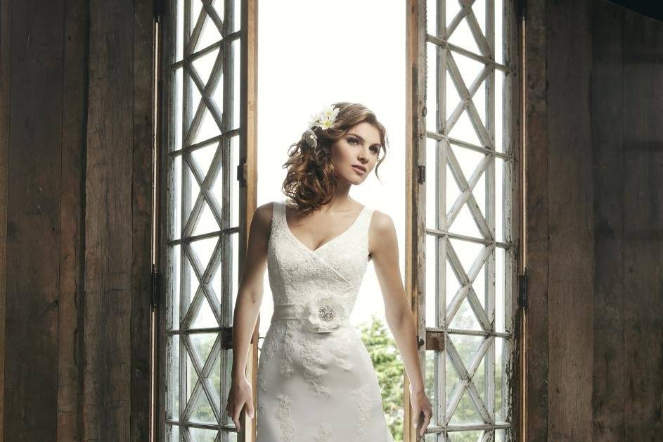 Style #3663
Satin sleeveless v neckline with lace appliques with modified A-line skirt with floating appliques chapel train, buttons down the back with detachable satin belt with lace and flower motif.