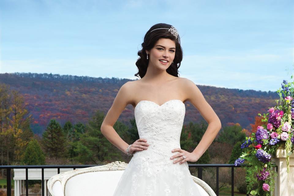 Style # 3801
Embroidered beaded lace gown featuring a sweetheart neckline and a basque waist on a tulle A-line skirt with floating beaded lace appliques. The back of the gown is finished with tulle covered buttons over the back zipper and a chapel length train.
