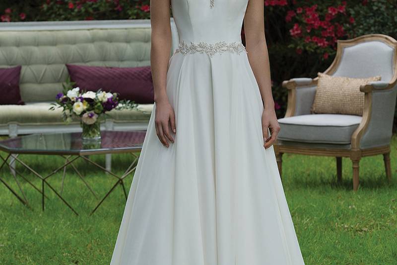 3952 <br> Make an entrance in this metallic beaded A-line gown. It features a Sabrina neckline, natural waist accented with beaded trim, illusion back, full skirt, and chapel length train.