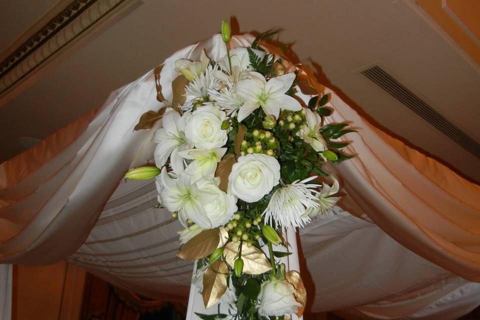 Corner of the Chuppa is decorated with roses, lilies, ruscus and lemon leaf hand-painted gold strung on gold bullion wire.