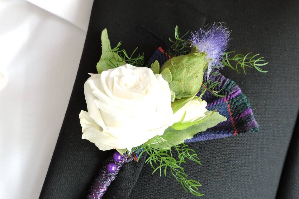 A bit of Scottish heritage is incorporated into the boutonniere with thistle and the family plaid.