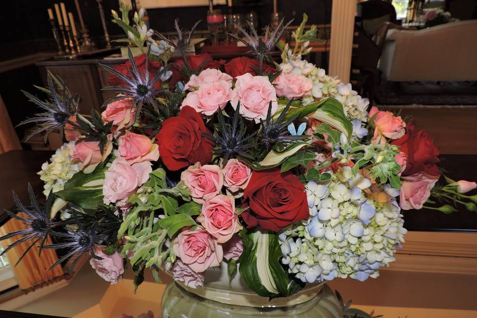 Hydrangeas, eryngium and roses in blues, pinks and reds make a statement for any table. Size can be adapted for a centerpiece.
