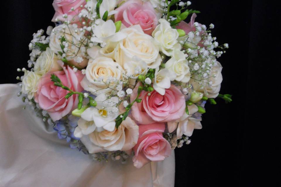 Blue hydrangea, white and pink roses, freesia, and babys breath showcase this elegant spring bouquet