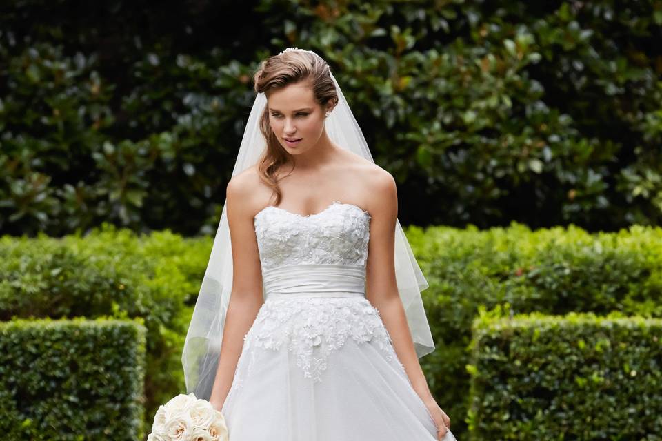 Style 14426 Clara <br> This figure hugging, shimmer taffeta, fit and flare gown features a ruched bodice, sweetheart neckline and a tulle train adorned with shimmer taffeta flowers that trickle down for added drama. Chapel train.