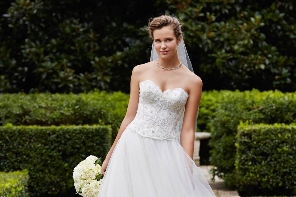Style 14430 Selena <br> Simple and stunning, this tulle ballgown features a silky taffeta ruched bodice and waistband, sweetheart neckline, and multi-layer skirt with horsehair hem. Two silky taffeta and tulle flowers with crystal centers accent the back bodice perfectly. Chapel train.