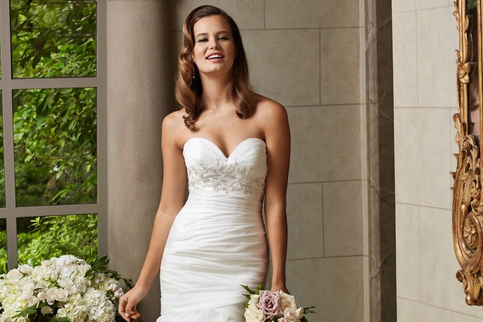 Style 16718 Catherine <br> This wedding dress marries a timeless shape with a hue that’s very of-the-moment. The sweetheart neckline bodice is adorned with all-over ivory Theodosia lace. The soft netting skirt is lined with stretch satin in a beautiful rose gold shade. The waist is finished with a matching, double-faced satin ribbon. And in the back, a low V is finished with a single row of pearl buttons. A dramatic puddle train is a glamorous flourish. It’s a perfect find for the bride seeking a modern and sophisticated take on romance.
