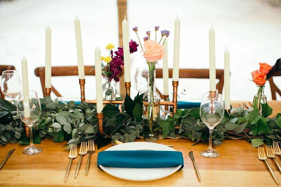 Wedding centerpiece with copper pipe candle holders and greenery