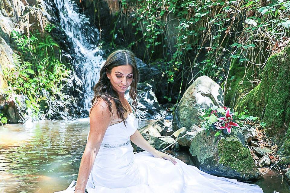 Bride sitting in waterfall