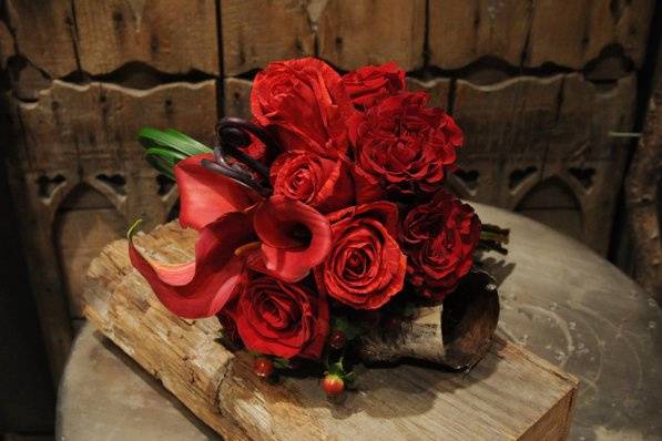 This rich red bridesmaid's bouquet features calla lilies, roses, and fiddlehead ferns.