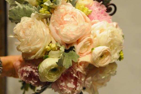 Open peonies, ranunculus, and garden roses harmonize with hyacinth and fiddlehead ferns in this fragrant bridal bouquet.