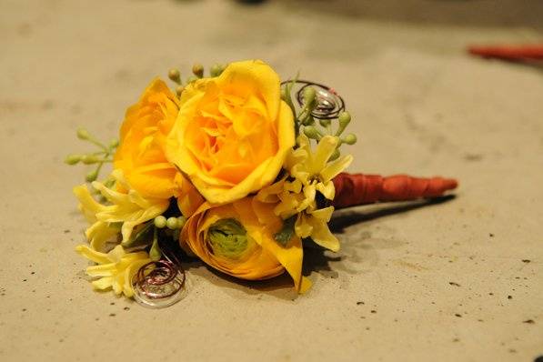 Golden yellows usher in the feel of spring in this boutonniere comprised of spray roses, ranunculus, and eucalyptus seeds.