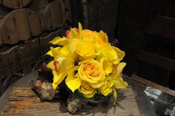 Cheerful yellow roses, cymbidiums, and callas are featured in this classic, bold, monochromatic bridesmaid's bouquet.