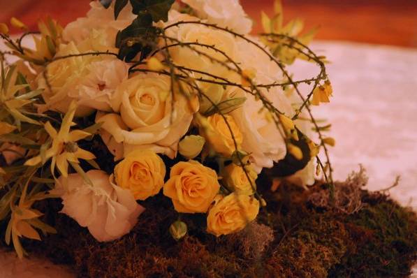 This centerpiece creates a lush spring landscape with yellow roses, vines and moss.