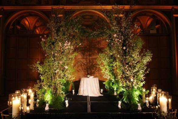 A non-traditional chuppah with flowering spring branches frames the wedding party.  Numerous pillar candles create an elegant, romantic atmosphere.