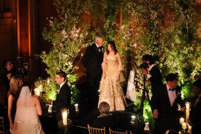 A non-traditional chuppah with flowering spring branches frames the wedding party.