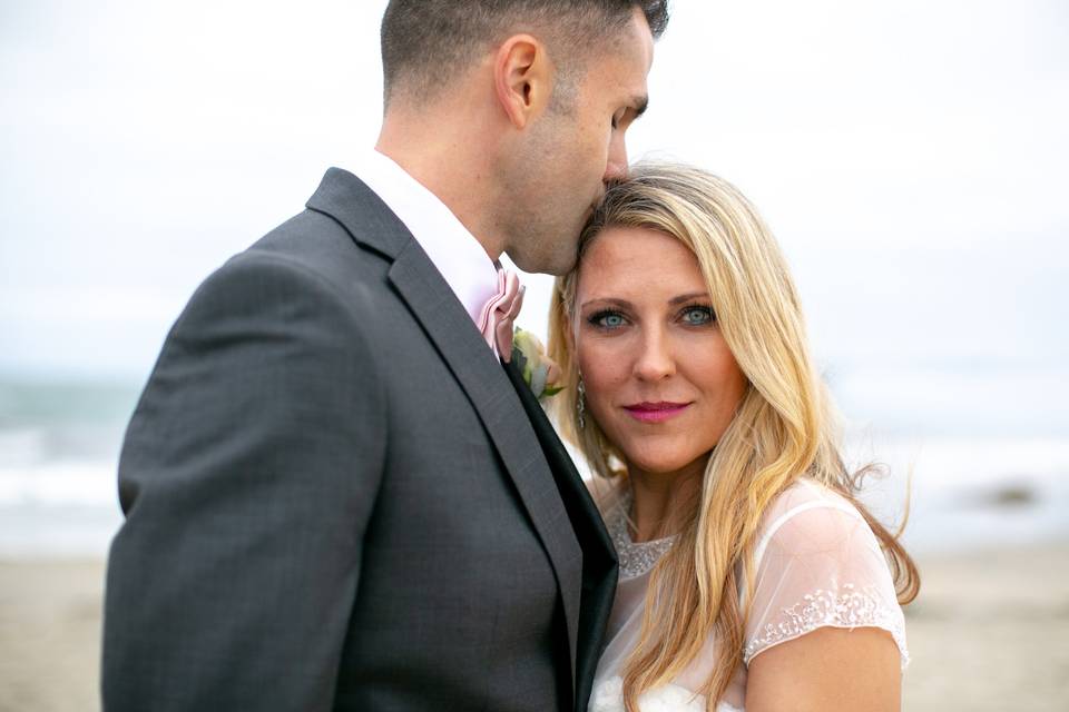 Groom kissing bride on head