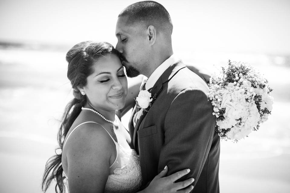 Groom kissing bride on head