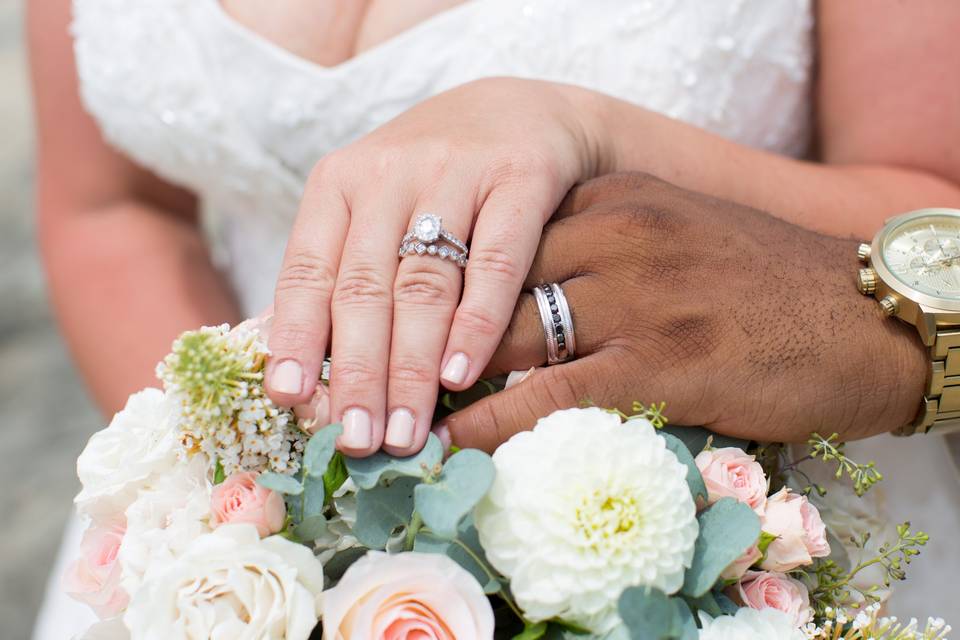 Hands on bouquet with rings