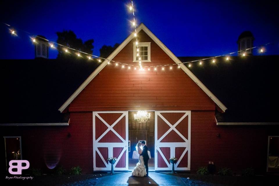 Main entrance to barn capturing the reflection from the rain and the glow of the chandelier and bistro lights.