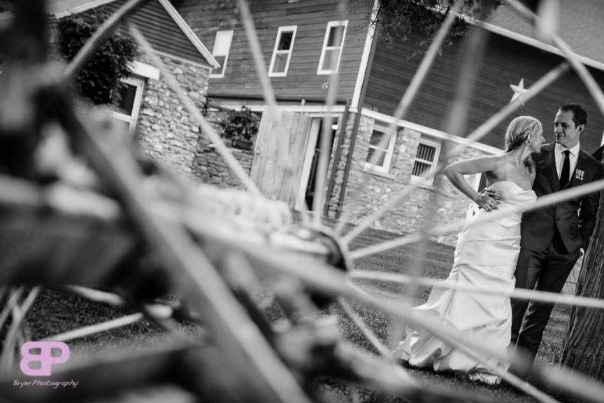 Black and white photo seen through the wheel of antique farm equipment.