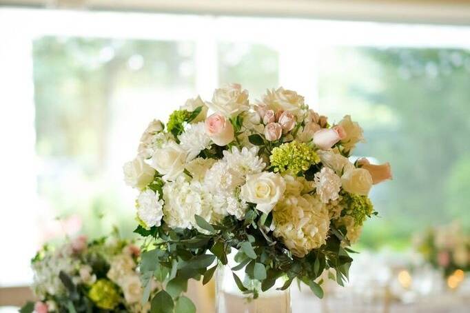 Tall clear square vase with open flower orb of hydrangeas, roses and other wildflowers