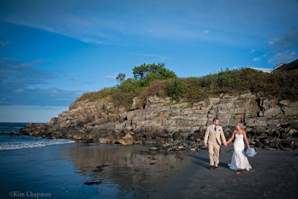 Bridal couple walks on beach. Photo session on beach, on cliff, by harbor, while guest enjoy cocktail hour.