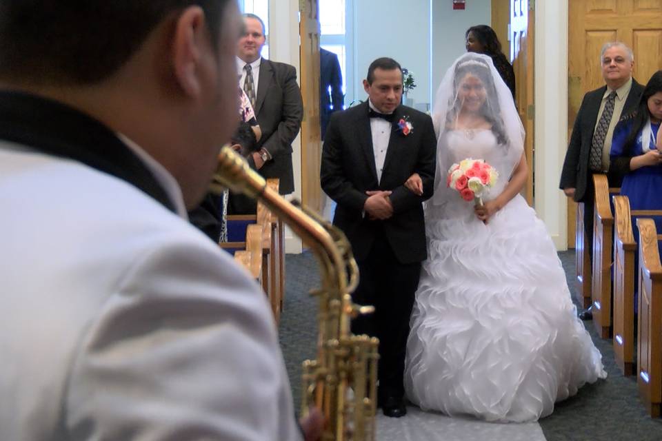The groom playing the saxophone as his bride walks down the aisle