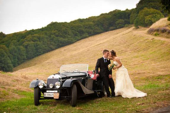 Newlyweds by a vintage coupe