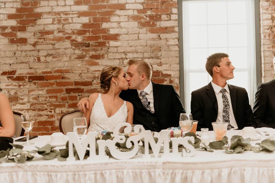 A kiss at the sweetheart table, Mariah Fox Photo