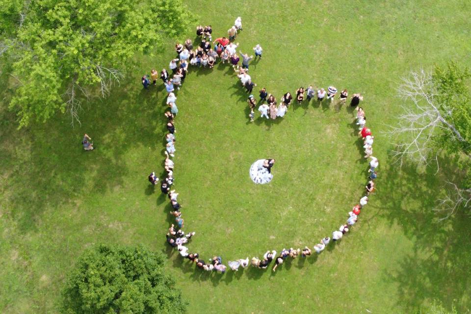 Drone footage of wedding guests in a heart shape