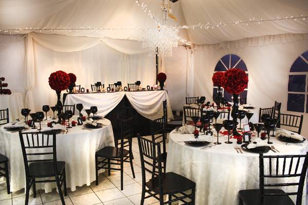 Vampire roses set above black wine glasses and china  with white table cloths and black chiavari chairs.