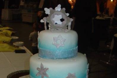 Winter-themed Snowflake cake, with airbrush detail & shimmery ribbons. Each of the snowflakes were cut by hand, airbrushed silver, and covered in delicate sparkles. Little lights were placed behind many of the snowflakes to make them glow as well.