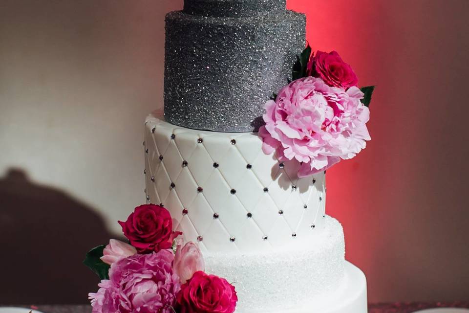 Glitz and rhinestones! Fondant wedding cake with quilting detail, covered in white and silver sparkle, and adorned with fresh floral bouquets.