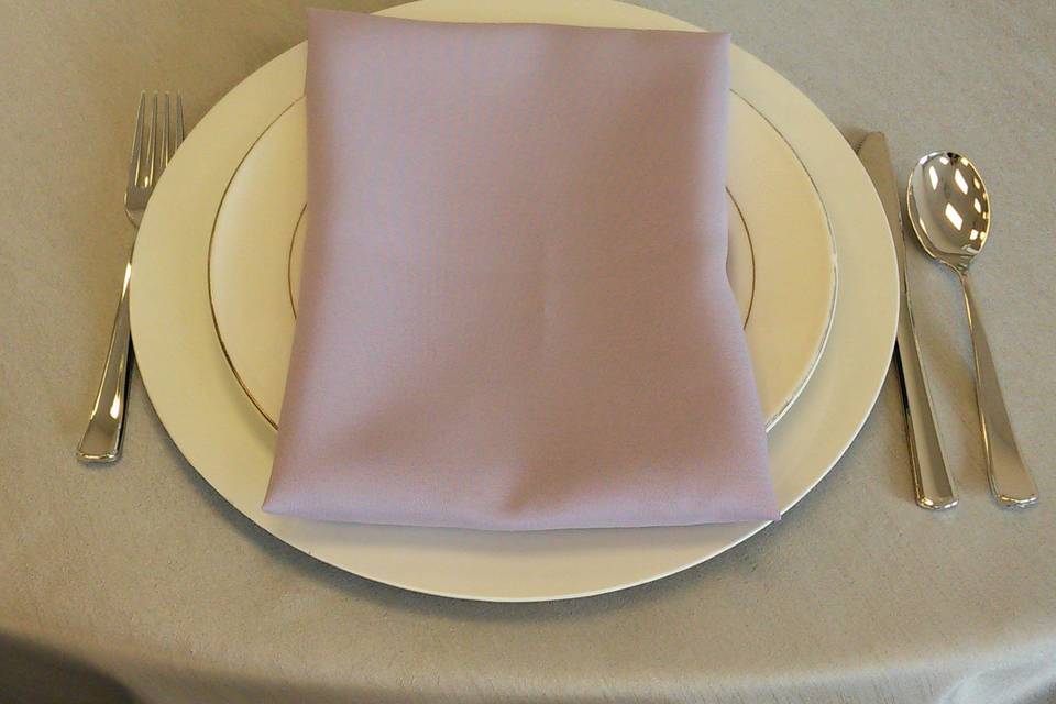 Silver dupioni table cover, white charger plate, white and silver china, lilac napkin.Rental items from Lake Party Rentals, Lake of the Ozarks, MO.