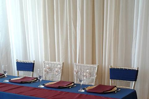 Head table with ivory and champagne drapes.
