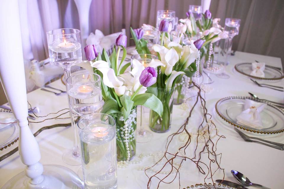 Cluster of Ivory Calla Lillies with pops of color in the tulips accented with pearls, curly willow and floating candles