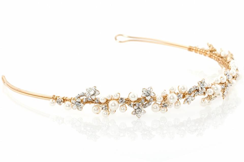 GOLDEN SHADOW TIARA
Richly textured yet light and dainty, this decadent golden tiara features ivory colored simulated pearls and crystals, set in a floral framework for an ethereal look. Set on a rhodium-plated brass setting, this piece is reminiscent of bohemian romance. The two holes on either ends make this tiara a versatile piece to wear both with a veil or without.
http://www.delilahk.com/delilahkbridal/bridal-hair-pieces/golden-shadow-tiara.html