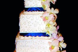 Colorful and glorious 4 tier buttercream cake with gorgeous azure colored ribbon work and flowers.