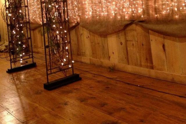 Side view of the wall of lights behind the arch which is covered in twigs and lights.