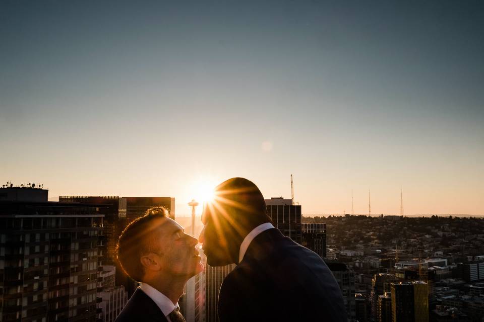 A same sex couple kiss during sunset at their downtown Seattle wedding.