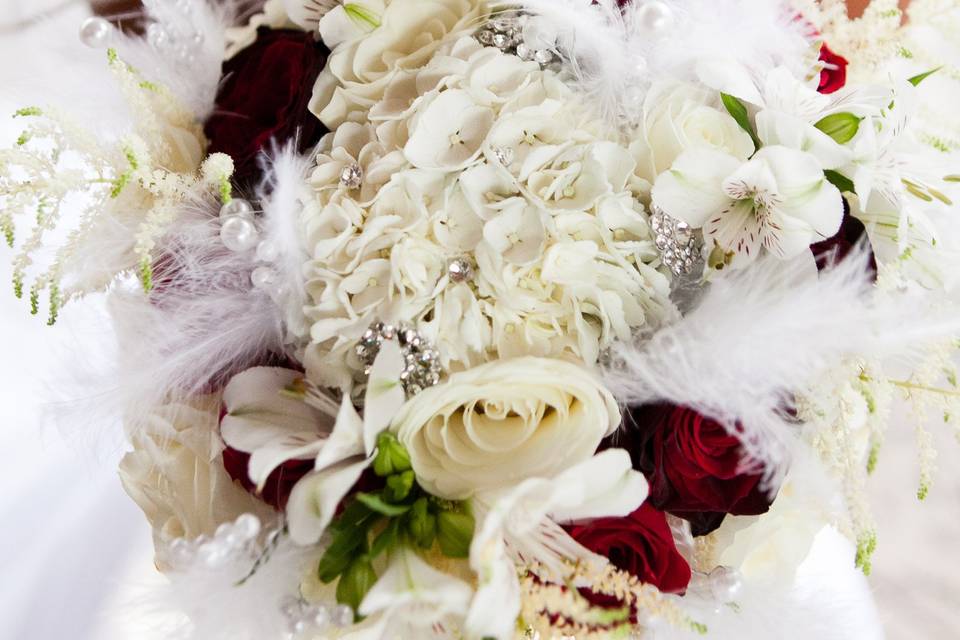 Hollywood glam bouquet with rhinestone inserts, hydrangea, roses, white astilbe, pearls, and feathers.