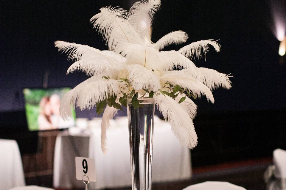 Gatsby Glam centerpiece with ostrich feathers, white hydrangea and completed with red votives at the base.