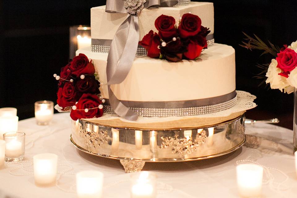 Gatsby Glam wedding cake with roses in various shades of red with white astilbe, pearls, silver ribbon and rhinestone brooch.