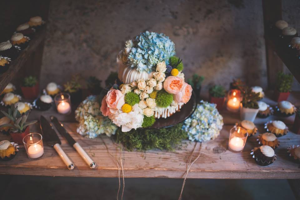 Nothing Bundt Cakes provided this 2 tiered wedding cake.  It was topped by blue hydrangea, peach garden roses, crespedia, sweetheart roses, and dianthus.  It was flanked by mini-bundts and candles.