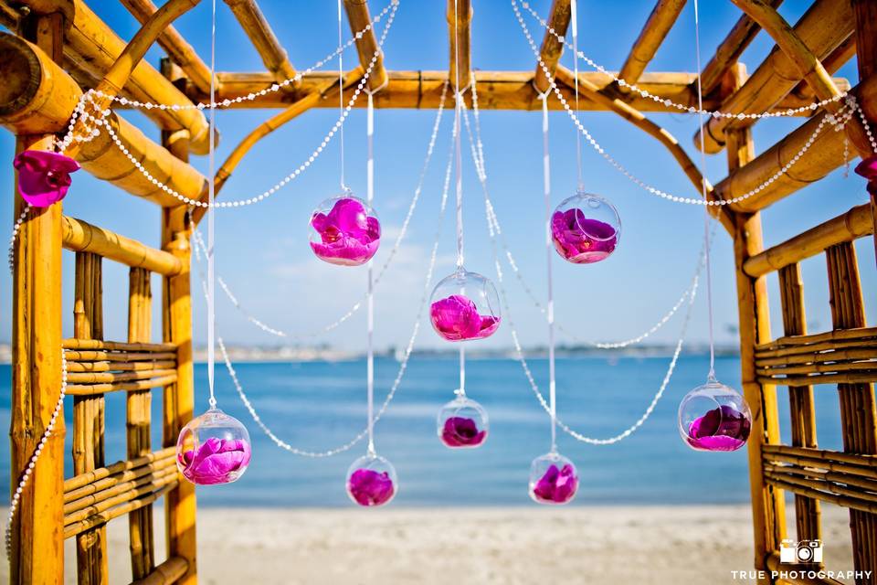 Bamboo arch with pearly beads and glass bulbs with fuchsia orchids create this romantic, clean look.