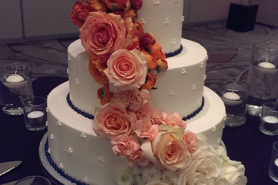 Simple cake design was brought to life with this orange to white ombre floral work.  Several shades of roses as well as ranunculus, tulips, mini carnations and pom poms were used to create this effect.