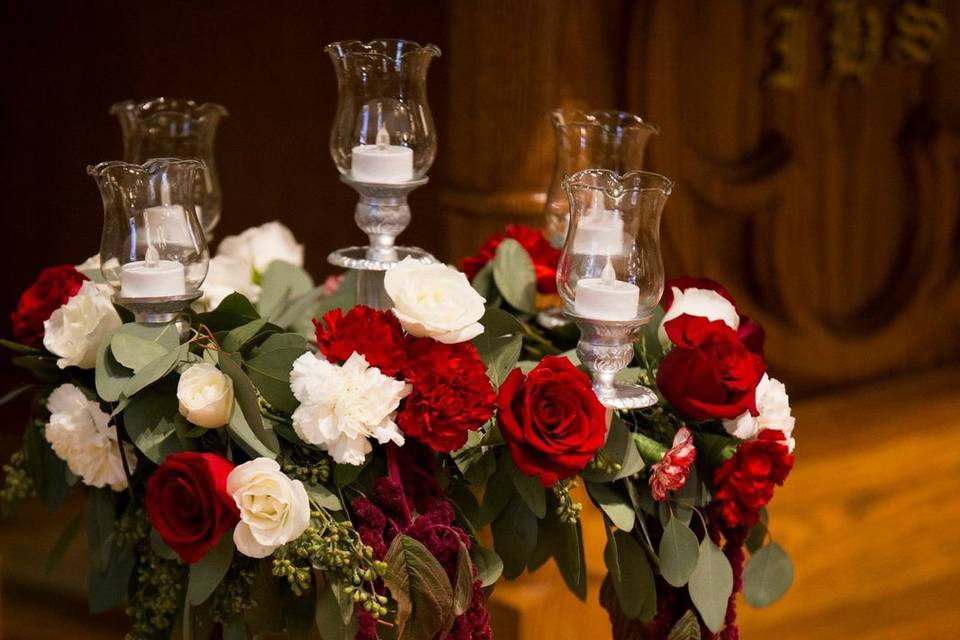 Candelabras with garland of roses, carnations, amaranthus, and seeded eucalyptus.