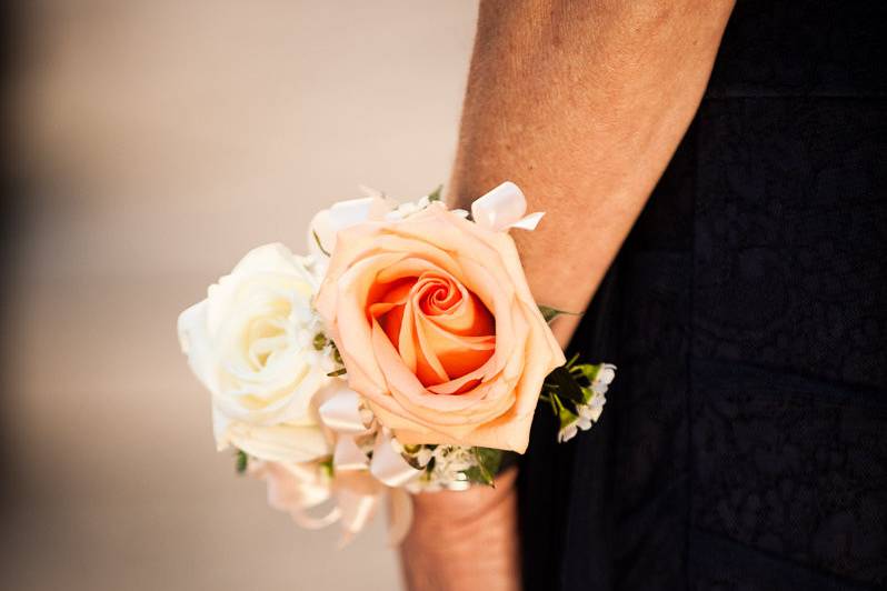 Peach and white rose corsage with peach ribbon and accents.