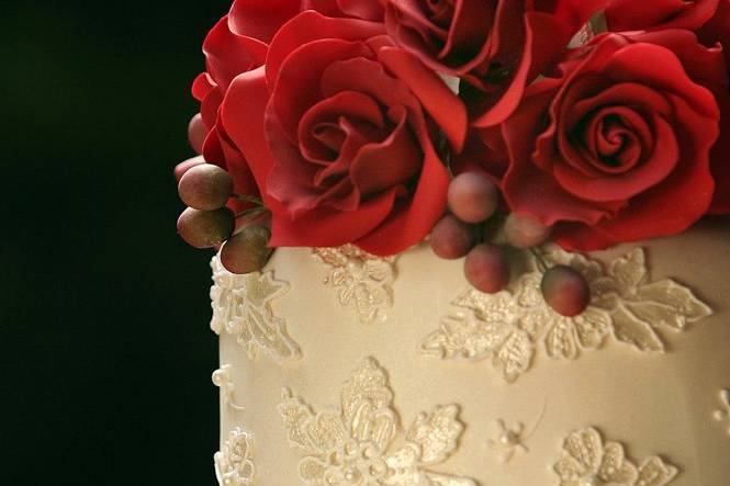 Ana Parzych Custom CakesCake topper detail consisting of Hand-crafted red sugar roses. Tiers are decorated with pressed fondant lace painted with edible pearl dust.